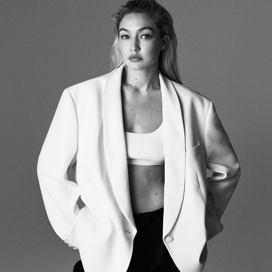 Black and white image of model Gigi Hadid wearing a white crop top and white blazer